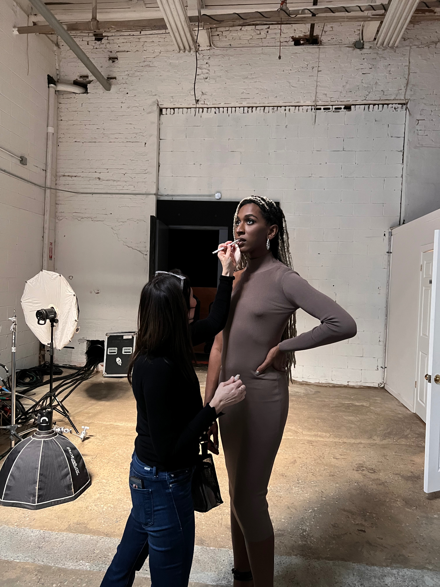 Shira applying lip liner to a model during a studio photo shoot