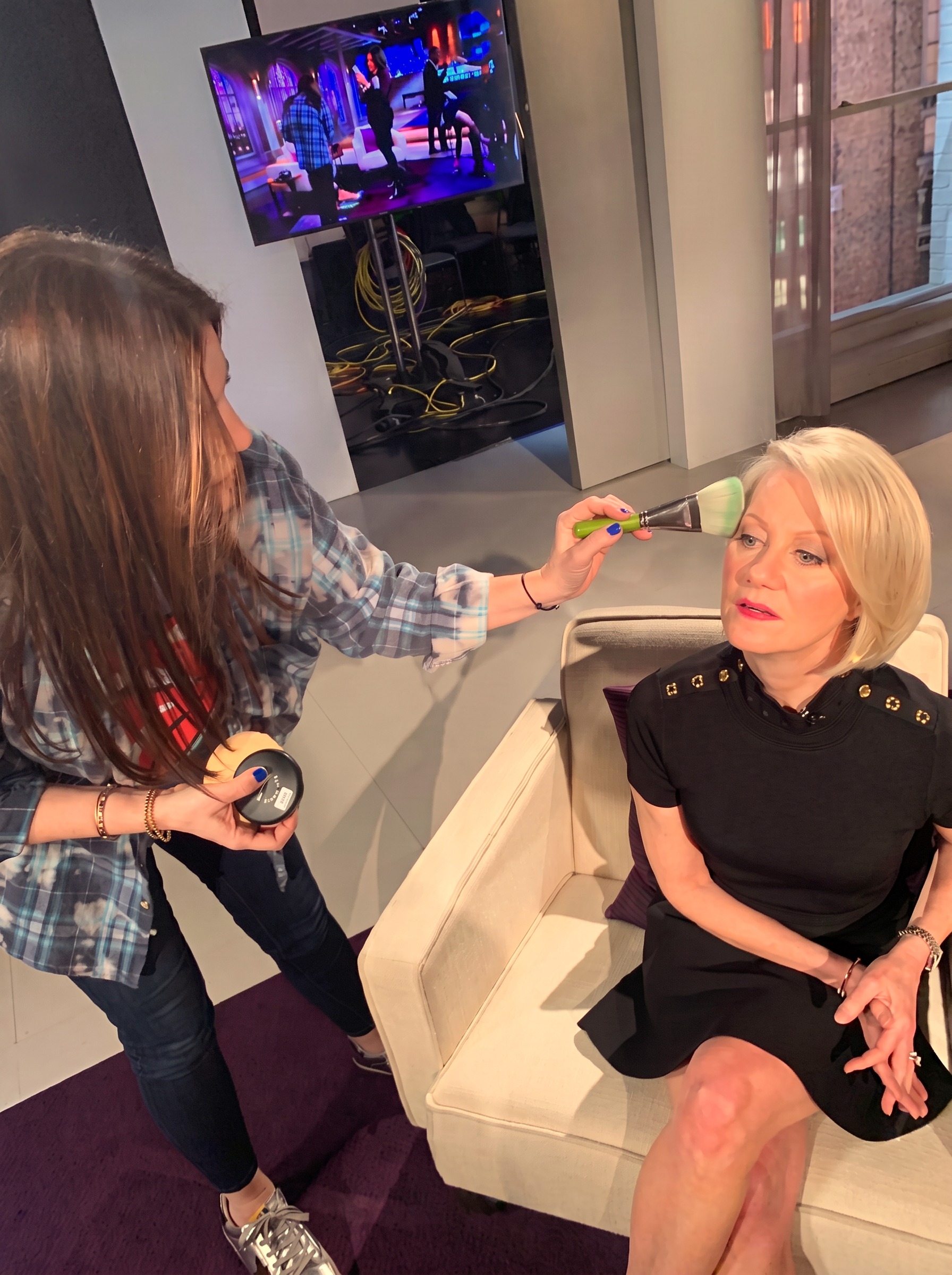 Shira powdering a television guest between takes on set