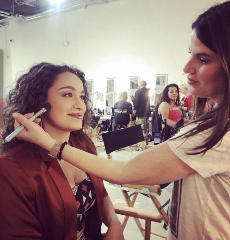 Shira applying blush to a model backstage before a shoot